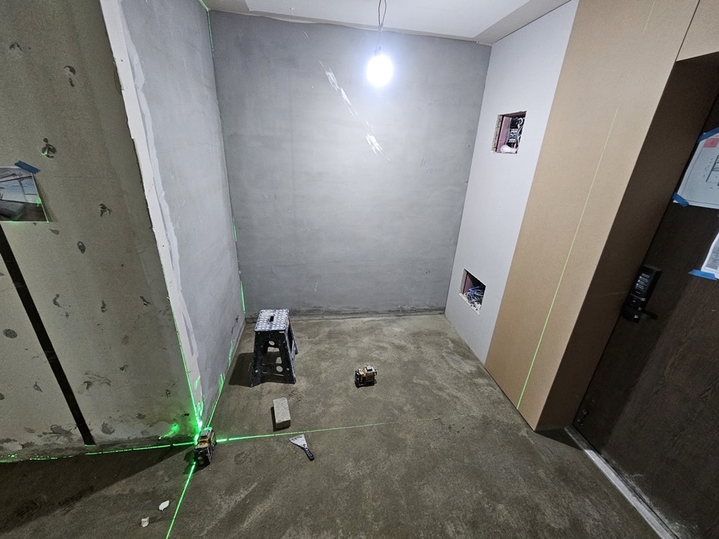 현관 바닥 미장 후 레벨기로 직각과 기준선을 확인하며 타일 레이아웃을 잡는 모습