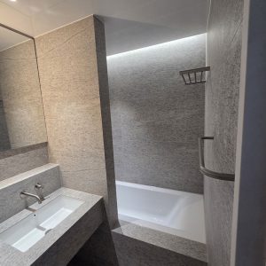 욕조 상부 간접조명이 설치된 분위기 있는 공용욕실 타일 마감