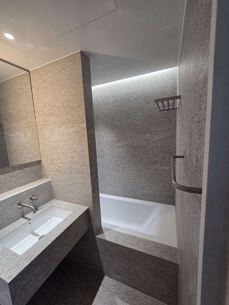 욕조 상부 간접조명이 설치된 분위기 있는 공용욕실 타일 마감