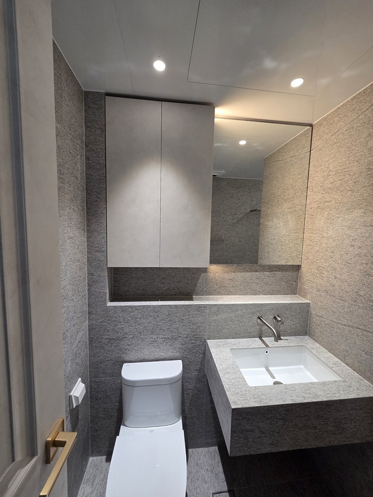 타일세면대 상부 거울과 수건장이 설치된 공용욕실 세면대 공간