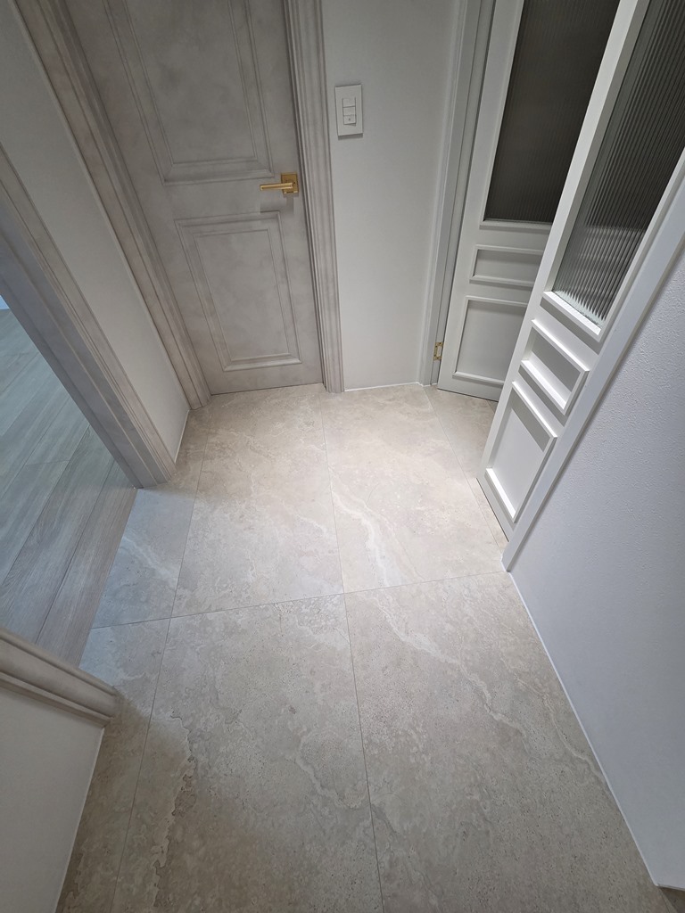 중문을 넘어 거실 바닥과 자연스럽게 이어지는 현관 타일 모습